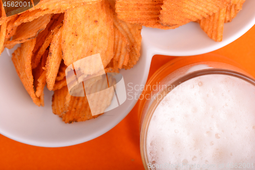 Image of Glass of light beer and potato chips on a abstract background. top view