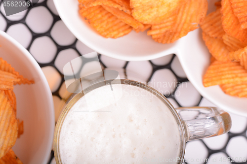Image of Glass of light beer and potato chips on a abstract background. top view