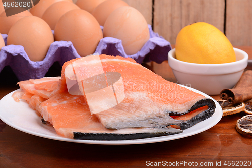 Image of fresh salmon fillet close up on white plate. eggs, cinnamon and lemon