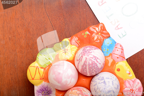 Image of Easter eggs and white paper on a wooden background