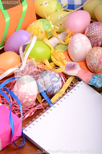 Image of Handcrafted easter eggs close up, white notepad, ribbons and decoration