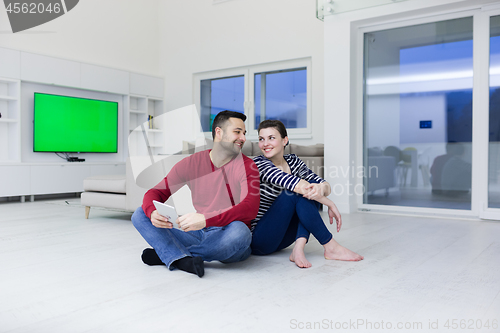 Image of Young Couple using digital tablet on the floor