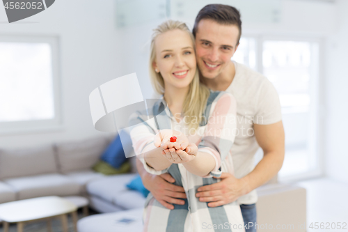 Image of couple showing small red house in hands