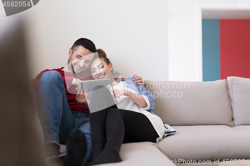 Image of couple relaxing at  home with tablet computers