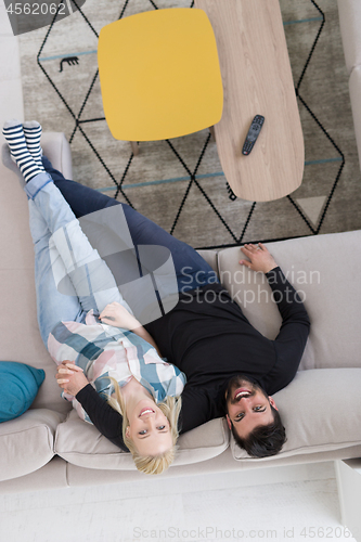 Image of Young couple on the sofa watching television top view