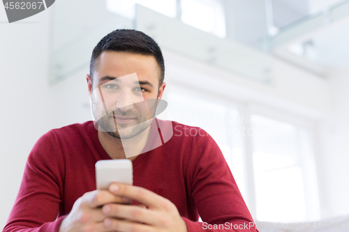 Image of young man using a mobile phone  at home