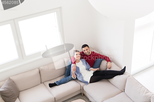 Image of couple relaxing at  home with tablet computers