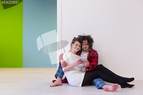 Image of Young Couple using digital tablet on the floor