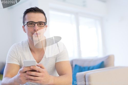 Image of young man using a mobile phone  at home