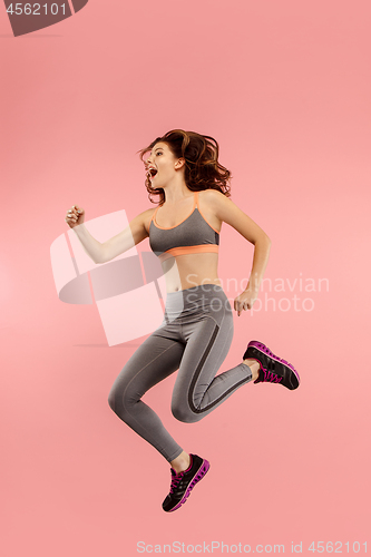 Image of Freedom in moving. Pretty young woman jumping against orange background