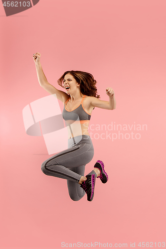 Image of Freedom in moving. Pretty young woman jumping against orange background