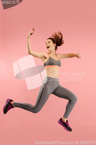 Image of Full length of pretty young woman with mobile phone while jumping