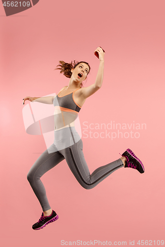 Image of Full length of pretty young woman with mobile phone while jumping