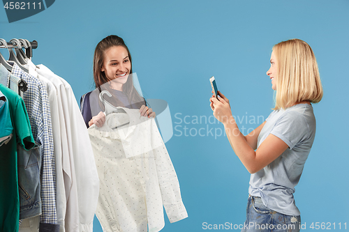 Image of The two young pretty girls looking at dresses and try on it while choosing at shop