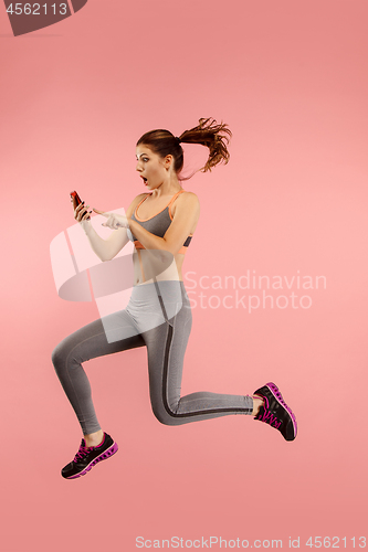 Image of Full length of pretty young woman with mobile phone while jumping