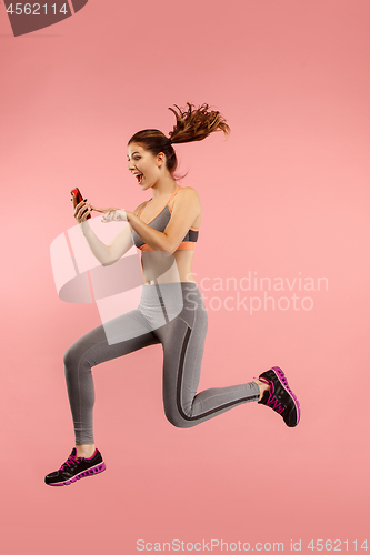 Image of Full length of pretty young woman with mobile phone while jumping