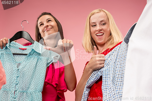 Image of The two young pretty girls looking at dresses and try on it while choosing at shop