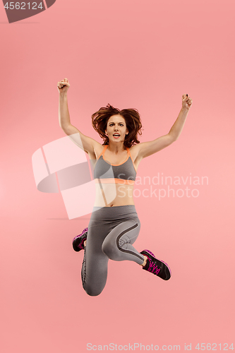 Image of Freedom in moving. Pretty young woman jumping against orange background