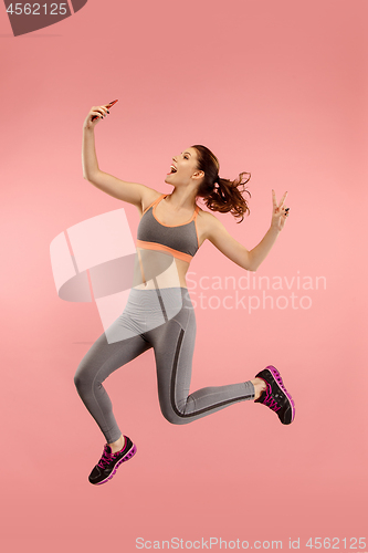 Image of Full length of pretty young woman with mobile phone while jumping