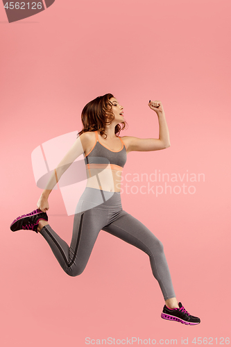 Image of Freedom in moving. Pretty young woman jumping against orange background