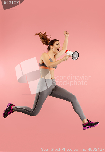 Image of Beautiful young woman jumping with megaphone isolated over red background