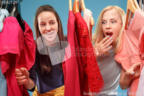 Image of The two young pretty girls looking at dresses and try on it while choosing at shop