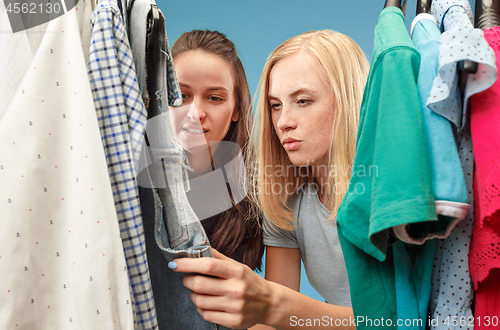 Image of The two young pretty girls looking at dresses and try on it while choosing at shop