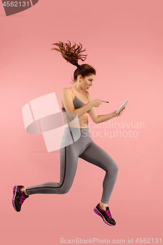 Image of Full length of pretty young woman with mobile phone while jumping