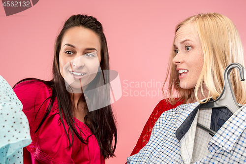 Image of The two young pretty girls looking at dresses and try on it while choosing at shop