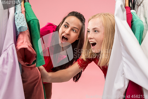 Image of The two young pretty girls looking at dresses and try on it while choosing at shop