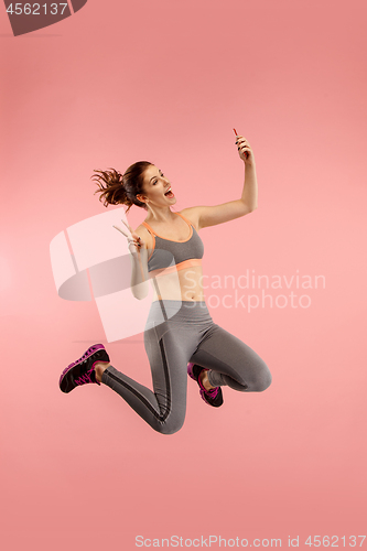 Image of Full length of pretty young woman with mobile phone while jumping