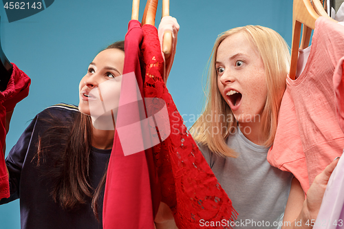 Image of The two young pretty girls looking at dresses and try on it while choosing at shop