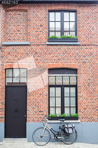 Image of Bruges, Belgium - August 16, 2013: View of the wall with windows, dark door and vintage bike with bag