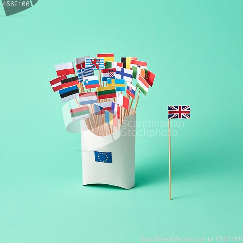 Image of Paper flag of Britain and a cardboard box with a sign of the EU and different flags on a green background with copy space. The exit of Britain from EU