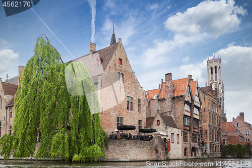 Image of Bruges, Belgium - May 17, 2012: The famous Belfry tower, old houses and a street cafe on the water channel in Bruges on a sunny day