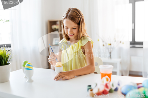 Image of happy girl coloring easter eggs at home