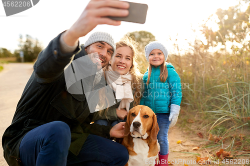 Image of happy family with dog taking selfie in autumn