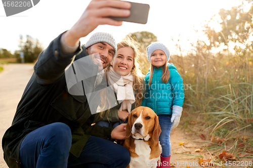 Image of happy family with dog taking selfie in autumn