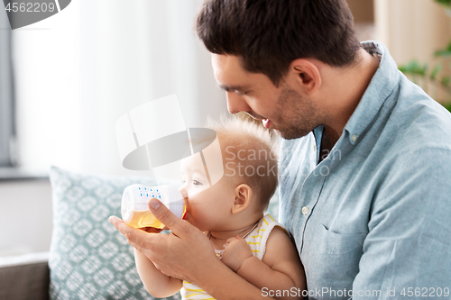 Image of father giving baby daughter to drink from bottle