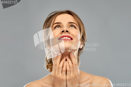 Image of smiling young woman touching her neck