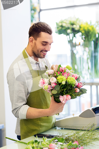 Image of smiling florist man making bunch at flower shop