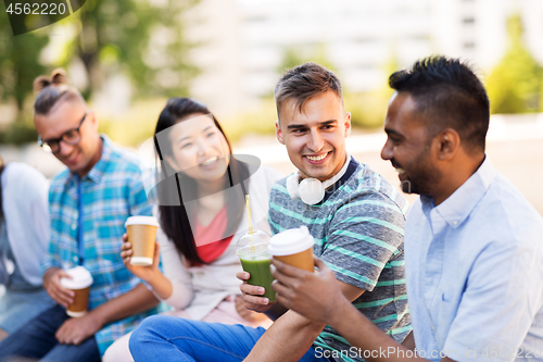 Image of friends drinking coffee and juice talking in city