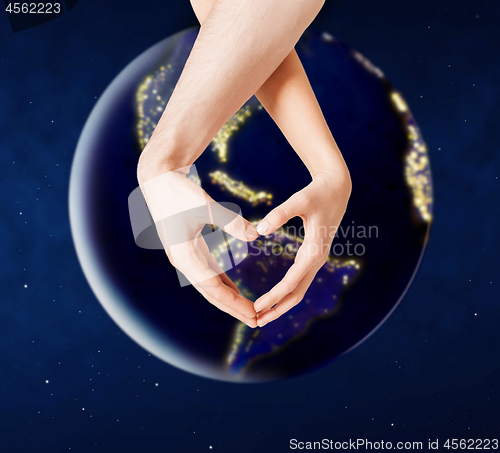 Image of hands showing heart gesture over earth in space