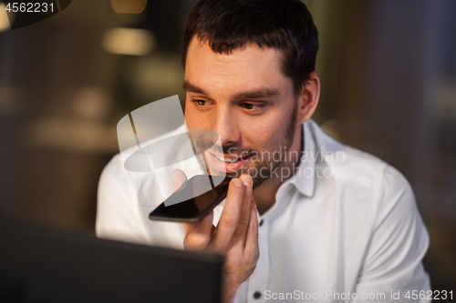 Image of businessman recording voice message on smartphone