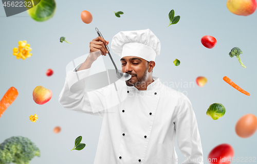 Image of happy male indian chef tasting food from ladle