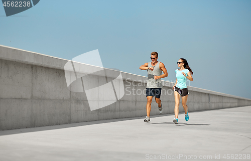 Image of couple in sports clothes running outdoors