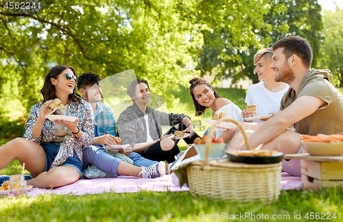 Image of happy friends eating sandwiches at summer picnic