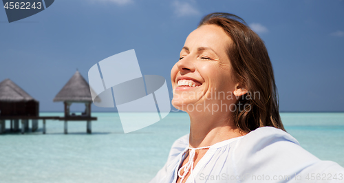 Image of happy woman over beach and bungalow on background