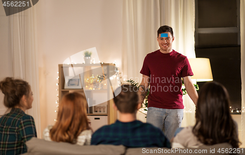 Image of friends playing guessing game at home in evening