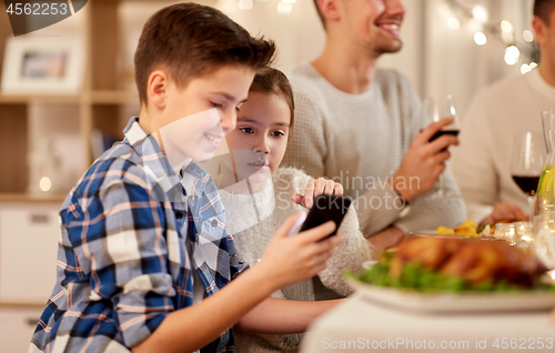 Image of boy with sister using smartphone at family dinner